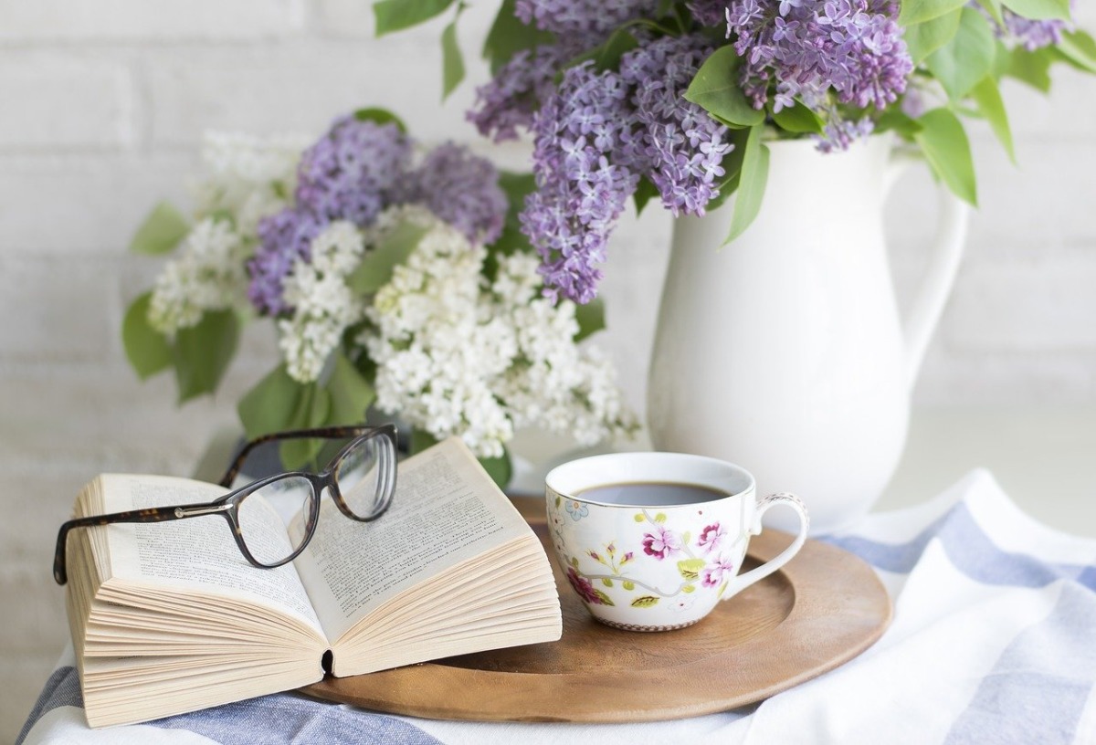 テーブルに置かれたコーヒーと本と眼鏡